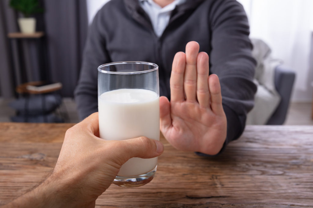 Man Refusing Glass Of Milk Offered By Person