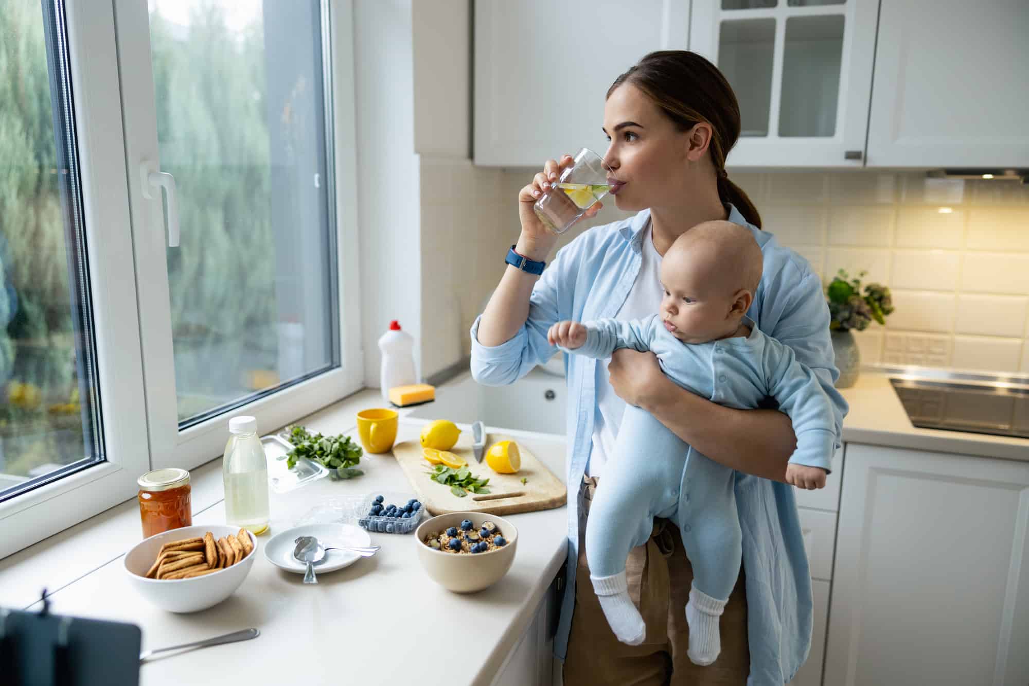 Happy Young Mother Standing With Her Baby In The Kitchen
