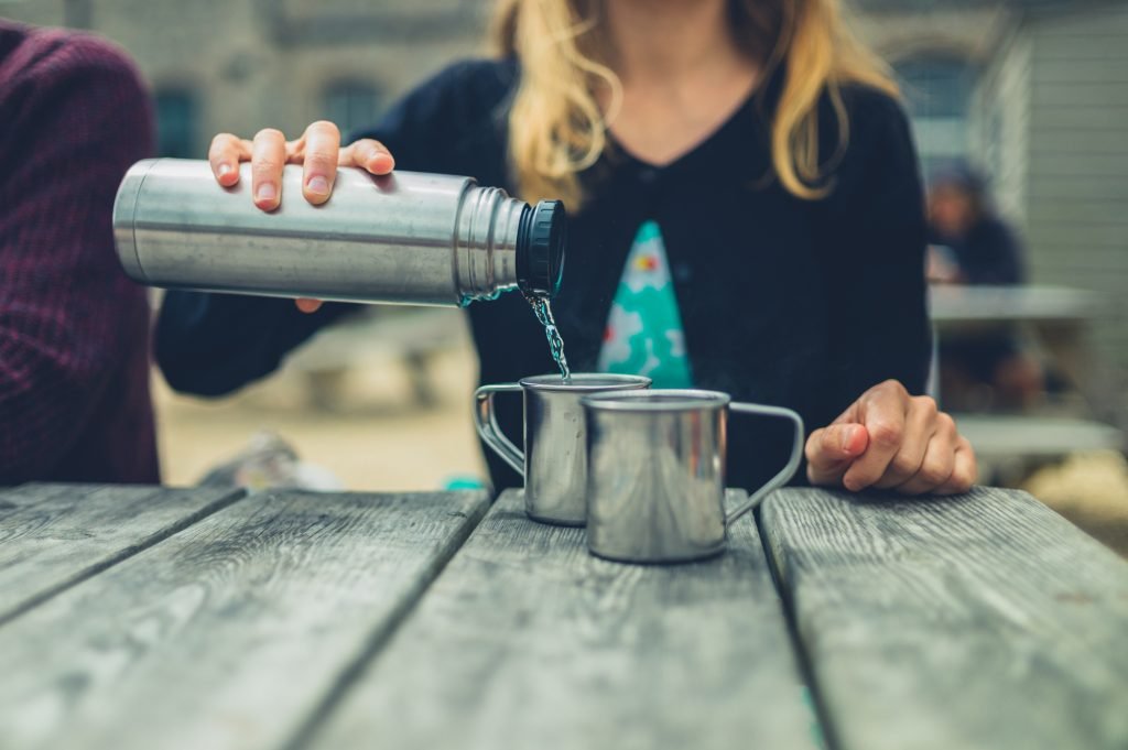 Young Woman Pouring Water From Flask Outside